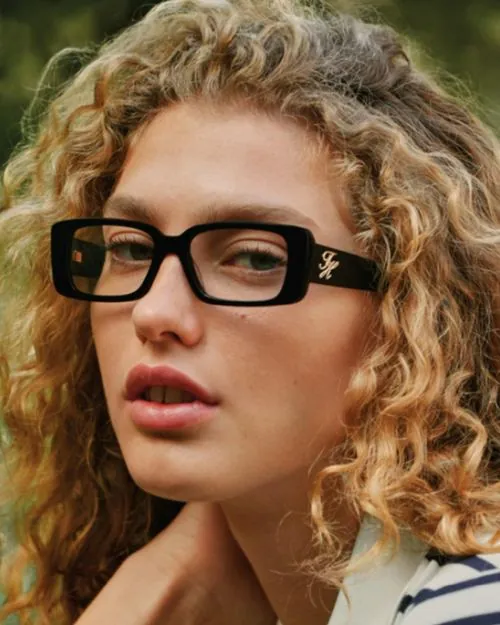 Mujer con aros oftálmicos Tommy Hilfiger rectangulares de acetato negro, disponibles en Ópticas CV+